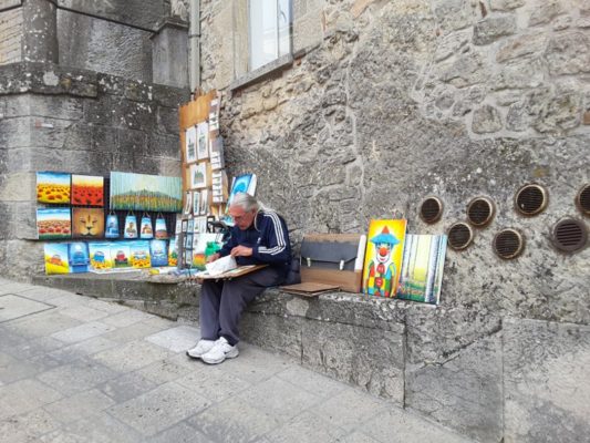 Artista che espone le sue opere nei vicoli di San Marino